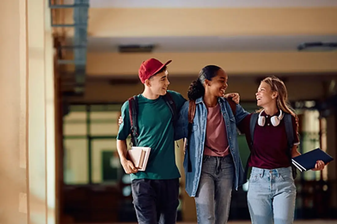 Adolescentes conversando enquanto caminham por um corredor de escola